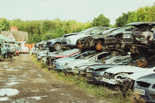 A scrap yard with lots of cars piled up